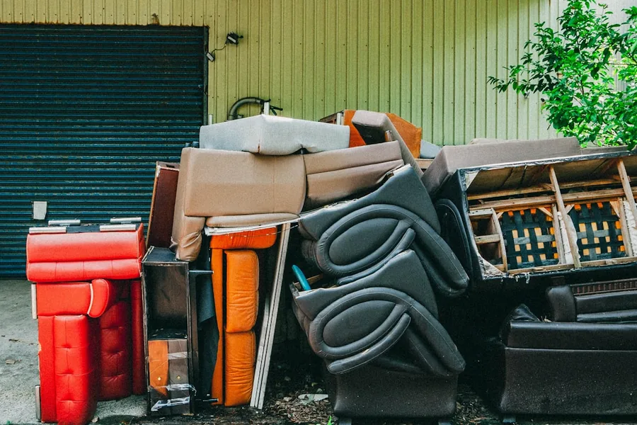 Old furniture, coolers and cabinets stacked against a wall for disposal