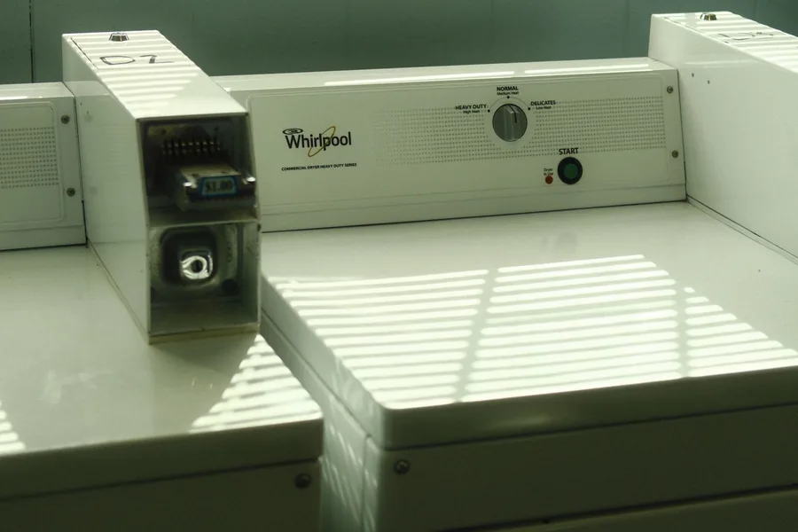 An old washer and dryer standing side by side in a dim laundry room